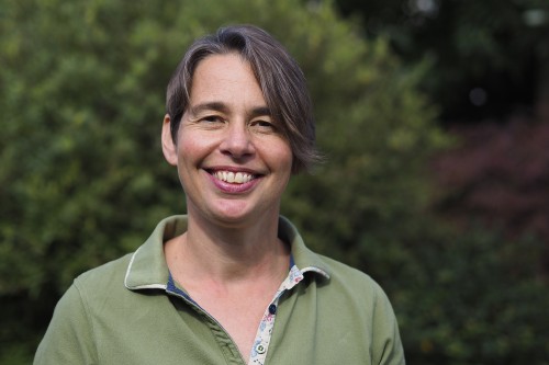 A photo of workshop leader Sarah Hoare, smiling against a leafy background